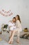 Young parents lift their baby in their arms and smile at him against the background of a bedroom decorated for Christmas and New