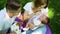 Young parents sitting with sweet baby and pet in summer park