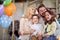 Young parents and their kids enjoy posing for a photo while sitting on the swing together at home. Family, home, playtime