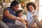 Young parents and their little daughter sitting on the floor at home and preparing a liquid to make soap bubbles. Family, home,