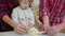 Young parents with toddler daughter have fun with dough in kitchen