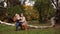 Young parents walking with daughter in forest in autumn