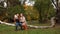 Young parents walking with daughter in forest in autumn