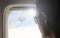 Young passenger looking out through window of the flying airplane. Side view of handsome man against plane window sitting and