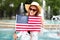 Young patriot woman in hat smilig and stretching USA flag in park