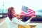 Young patriot woman in sunset with toothy smile stretching USA flag profile view