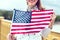 Young patriot woman with toothy smile stretching USA flag concept