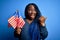 Young patriotic african american plus size woman with braids holding united states flags pointing and showing with thumb up to the