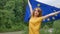 Young patriotic woman is holding a banner of European Union flag smiling and looking at the camera with proud of EU on