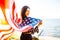 Young patriotic woman holds American flag in the wind on the beach on a sunset. 4th July, Independence day. Freedom, american