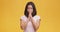 Young peaceful asian lady praying to God with closed eyes, keeping hands near face, orange studio background