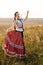 Young peasant woman, dressed in Hungarian national costume, posing over nature background