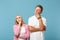 Young pensive couple two friends guy girl in white pink blank empty design t-shirts posing isolated on pastel blue