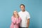 Young pensive couple two friends guy girl in white pink empty blank design t-shirts posing isolated on pastel blue