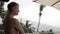 Young pensive man with a naked torso stands and watches the rain in a tropical island. slow motion