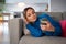 Young pensive woman in blue sweater reads bad news message from boyfriend in social media on phone