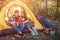 Young peoaple sitting in tent and look at each other. She holds opened book while guy has thermos in hands. She holds