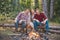 Young people eating roasted marshmallows while camping near campfire. Friends camping concept. Group of young people