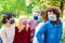 Young people having fun around city park during coronavirus outbreak.Happy multiethnical friends wearing face protective masks and