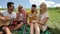 Young people listening guy playing guitar group friends summer day sitting green grass