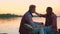 Young people in love sit on the stones against the background of the river, the guy kisses the girl on the forehead