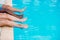 Young people lying near swimming pool. Cropped image of legs over blue water