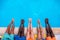 Young people lying near swimming pool. Cropped image of legs over blue water