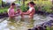 Young people play with a small child in the pond