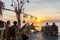 Young people relax in an outdoor bar on a cliff in the sunset