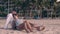 Young people rest on evening shore sand at sunset light