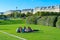 Young people rest on green lawn in park near architectural ensemble of Louvre, Paris, France