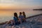 Young people sit on the beach and watch the sunset