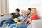 Young people with snacks watching TV on sofa