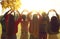 Young people standing in autumn park at sunrise and forming heart shapes with hands