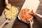 Young people taking slices of hot cheese pizzas from cardboard boxes at table, top view.