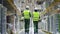 Young people workers talking and walking on industrial warehouse during working day.