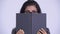 Young Persian businesswoman hiding behind book and thinking