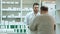 Young pharmacist and senior man customer with drug and prescription at drugstore