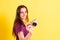 Young photography student girl holds a compact camera  isolated on yellow studio background