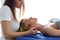 Young physiotherapist doing a neck treatment to the patient in a physiotherapy room.