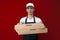 Young pizza delivery man in uniform on a red background gives a ready order, the courier guy holds pizza boxes