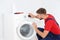 Young plumber examining washing machine