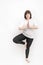 Young plump woman practices yoga. Portrait of girl in tree pose on white background