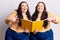 Young plus size twins holding book smiling happy pointing with hand and finger