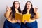 Young plus size twins holding book smiling happy pointing with hand and finger to the side