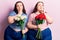 Young plus size twins holding flowers serious face thinking about question with hand on chin, thoughtful about confusing idea