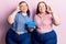 Young plus size twins holding vintage telephone doing ok sign with fingers, smiling friendly gesturing excellent symbol