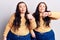 Young plus size twins wearing casual clothes doing thumbs up and down, disagreement and agreement expression