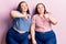 Young plus size twins wearing casual clothes doing thumbs up and down, disagreement and agreement expression