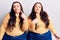 Young plus size twins wearing casual clothes pointing to both sides with fingers, different direction disagree